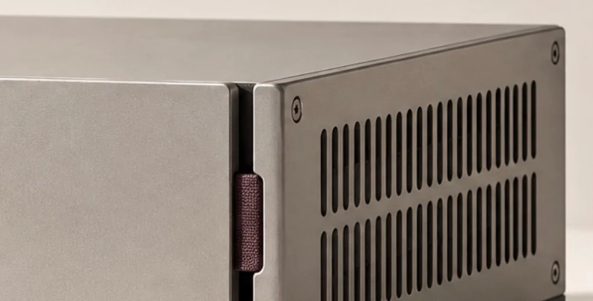 Detail of the same enclosure: plum fabric tab and silver side panel with vertical ventilation slots and a visible screw.